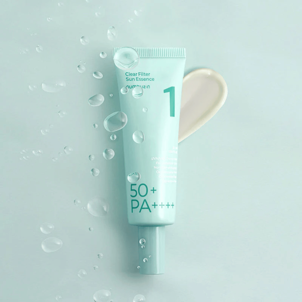 Ένας ανοιχτό μπλε σωλήνας με No.1 Clear Filter Sun Essence SPF 50+ PA++++. Ο σωλήνας είναι διακοσμημένος με σταγόνες νερού και μια δόση του προϊόντος εμφανίζεται δίπλα. Το προϊόν είναι σχεδιασμένο για να παρέχει υψηλό δείκτη προστασίας από τον ήλιο και προστασία από τις ακτίνες UVA/UVB.