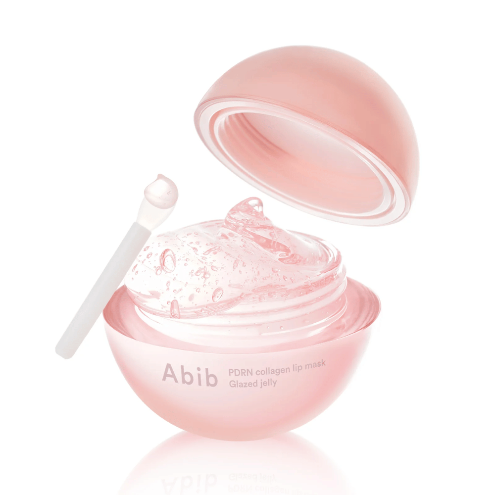 Ροζ στρογγυλό δοχείο με Abib PDRN Collagen Lip Mask Glazed Jelly, ανοιχτό με το καπάκι γερμένο προς τα πίσω. Διαφανές τζελ με φυσαλίδες αέρα φαίνεται στο δοχείο μαζί με μια μικρή σπάτουλα.