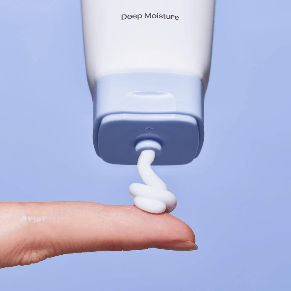1. Ma:nyo Panthetoin Cream – κοντινό πλάνο λευκής ενυδατικής κρέμας προσώπου που εφαρμόζεται από ανοιχτό μπλε σωληνάριο σε ένα δάχτυλο