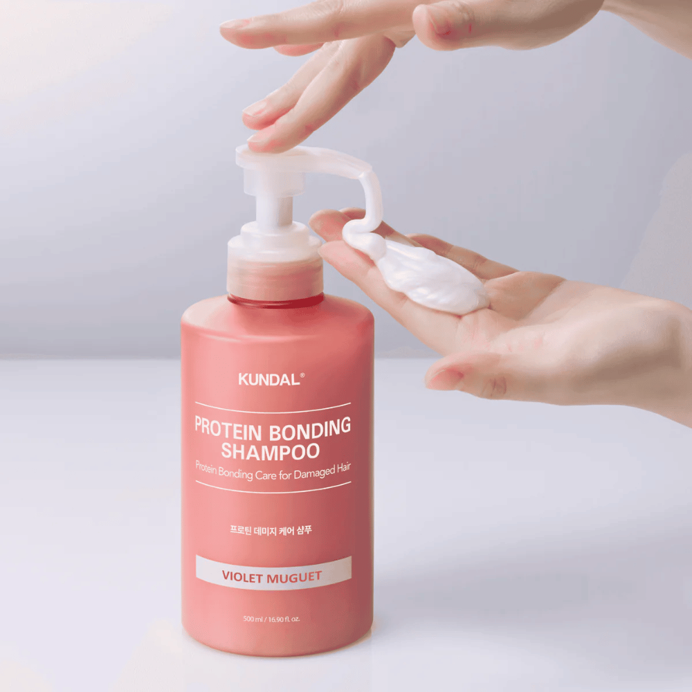 Χέρι αντλεί KUNDAL Protein Bonding Shampoo Violet Muguet σε κρεμώδη υφή, επανορθωτικό σαμπουάν για ταλαιπωρημένα μαλλιά.