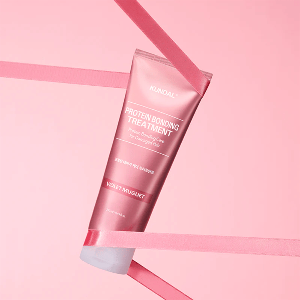 KUNDAL Protein Bonding Treatment Violet Muguet σε ροζ σωλήνα 250 ml σε ροζ φόντο με διακοσμητικές κορδέλες.