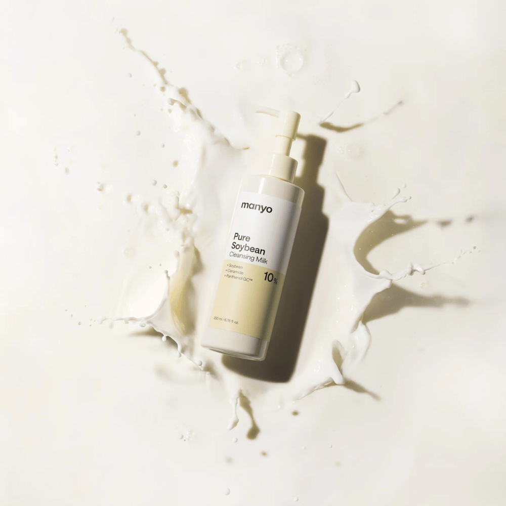 1. Ma:nyo Pure Soybean Cleansing Milk – απαλό καθαριστικό γαλάκτωμα με σόγια σε μπουκάλι με αντλία, περιτριγυρισμένο από πιτσιλιές γάλακτος σε ανοιχτόχρωμο φόντο