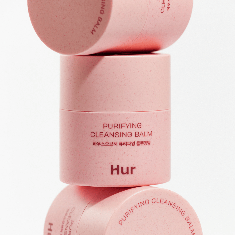 Πώς Purifying Cleansing Balm σε ροζ συσκευασία στοιβαγμένο στο στούντιο. Καθαριστικό cleansing balm που διαλύει αποτελεσματικά το μακιγιάζ, το σμήγμα και τις ακαθαρσίες χωρίς να ξηραίνει το δέρμα.