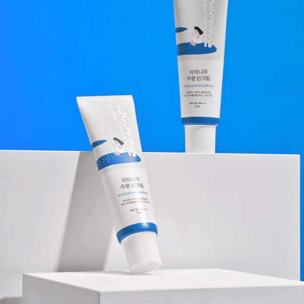 Δύο σωλήνες με Round Lab Birch Juice Moisturizing Sunscreen SPF50+ PA++++ 50ml που βρίσκονται πάνω σε μπλε φόντο.