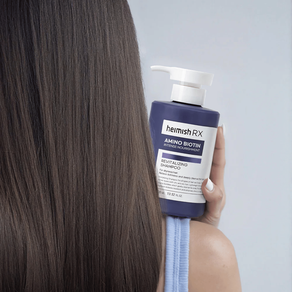 Heimish RX Amino Biotin Revitalizing Shampoo κρατιέται στο χέρι απέναντι από μακριά, λαμπερά μαλλιά – δείχνει το αποτέλεσμα της έντονης θρέψης και ενυδάτωσης για ξηρά μαλλιά.