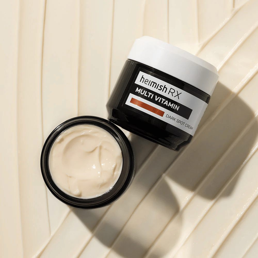 heimish RX Multi Vitamin Dark Spot Cream – μια θρεπτική κρέμα προσώπου για να μειώνει τις σκούρες κηλίδες και να δίνει στο δέρμα πιο ομοιόμορφο τόνο. Η απαλή υφή της κρέμας παρουσιάζεται σε ένα ανοιχτό βάζο με κομψή συσκευασία.