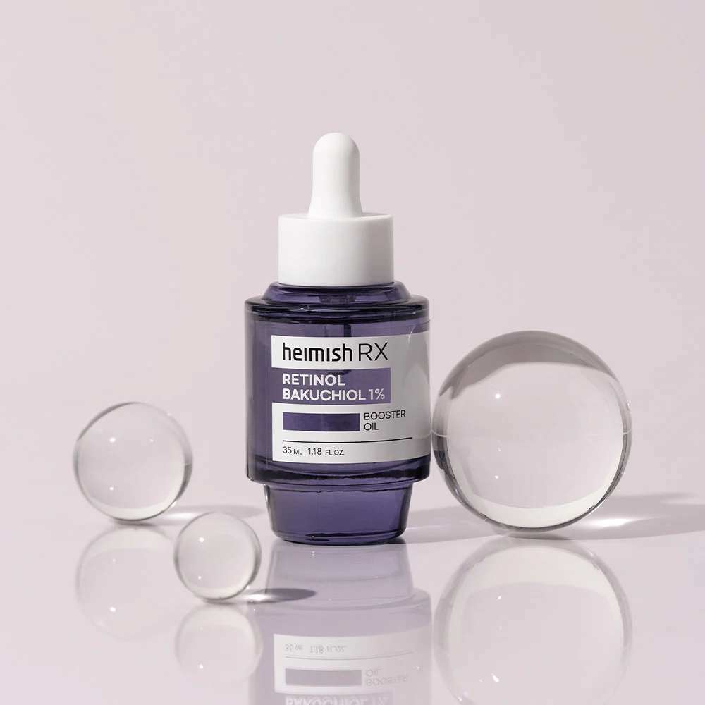 Heimish RX Retinol Bakuchiol Booster Oil 1% σε ένα κομψό μωβ γυάλινο μπουκάλι με πιπέτα. Το λάδι τοποθετείται σε μια ανακλαστική επιφάνεια με γυάλινες χάντρες γύρω του, προσδίδοντας μια πολυτελή και σύγχρονη αίσθηση.
