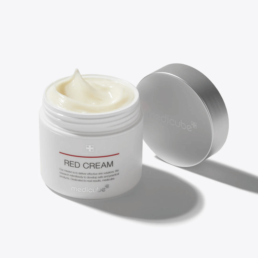 Ανοιχτό δοχείο με medicube Red Cream 50ml – μια ανοιχτόχρωμη κίτρινη κρέμα προσώπου σε λευκή συσκευασία με ασημένιο καπάκι, σχεδιασμένη για δέρμα με τάση ακμής.