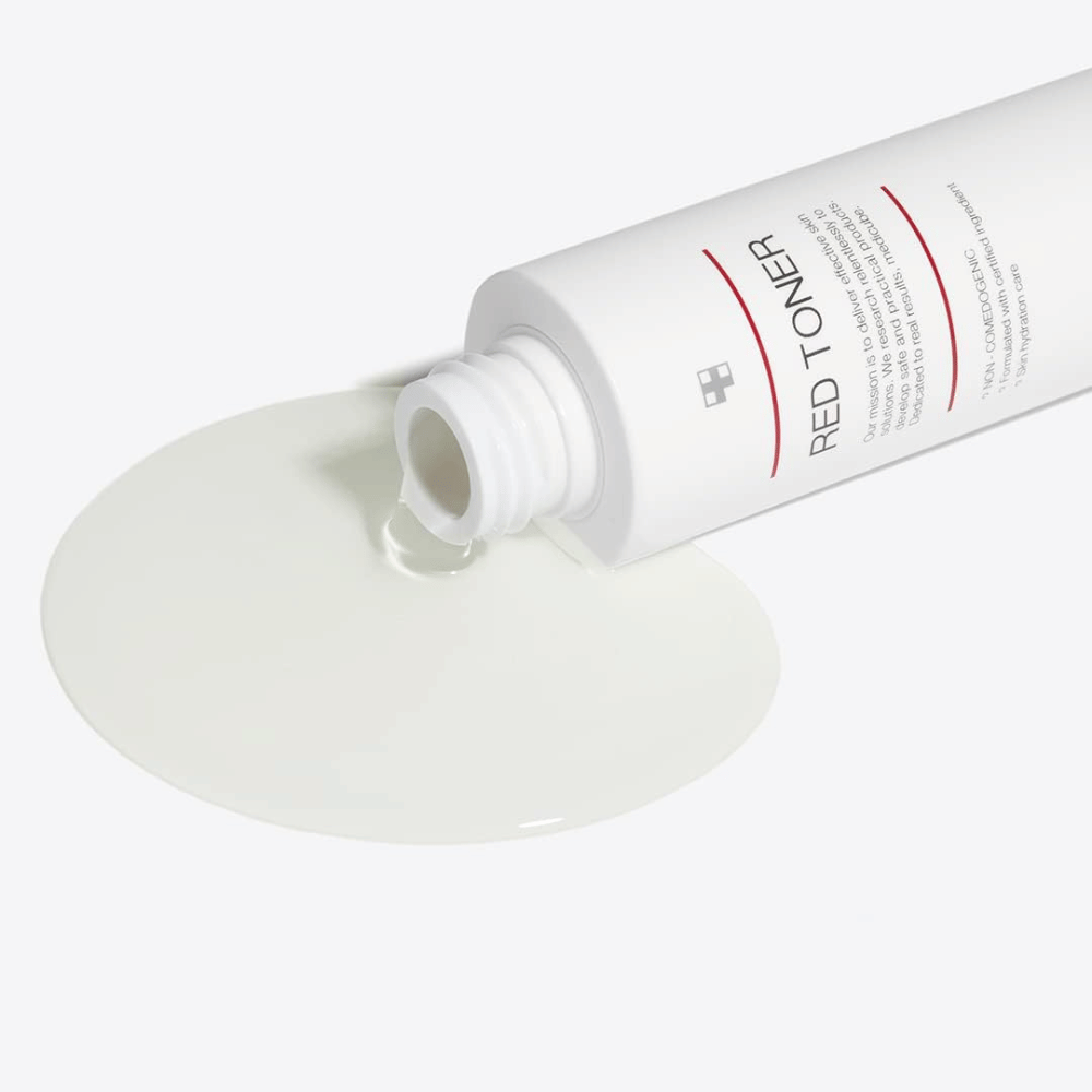 Ανοιχτό μπουκάλι με medicube Red Toner που χύνεται σε μια λευκή επιφάνεια – δείχνει την ελαφριά και υγρή υφή του προϊόντος.