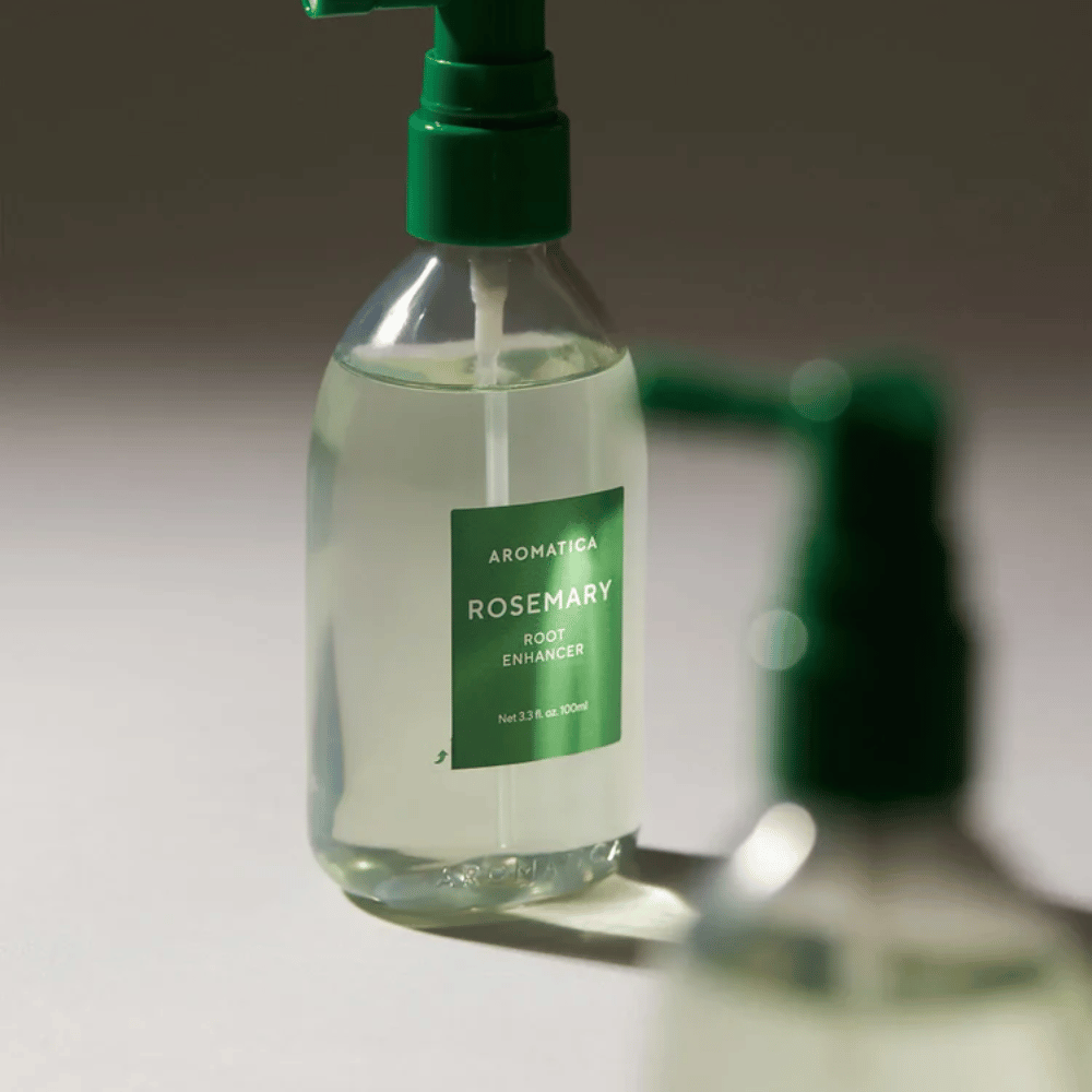 Κοντινό πλάνο του AROMATICA Rosemary Root Enhancer με πράσινο ρύγχος εφαρμογής. Η εικόνα εστιάζει στο σχέδιο του μπουκαλιού και στην ακριβή εφαρμογή απευθείας στο τριχωτό της κεφαλής.