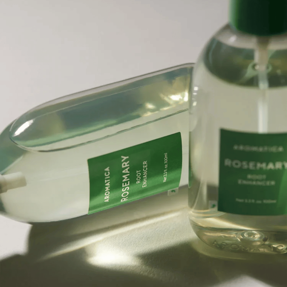 Δύο μπουκάλια AROMATICA Rosemary Root Enhancer με διαφανές προστατευτικό καπάκι και πράσινη ετικέτα. Κοντινό πλάνο που αναδεικνύει τον premium σχεδιασμό του προϊόντος και τη φυσική φιλοσοφία περιποίησης μαλλιών.