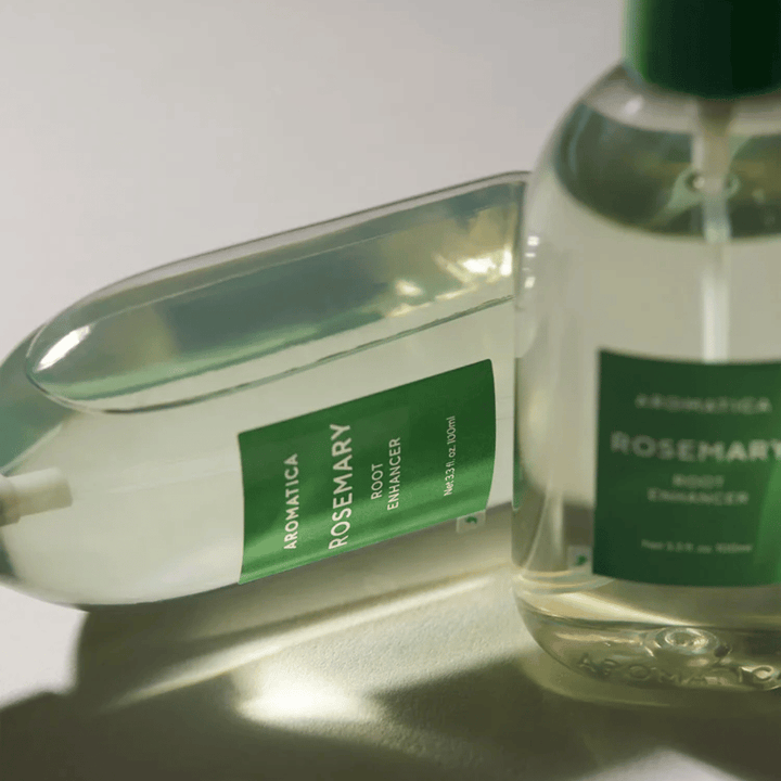 Δύο μπουκάλια AROMATICA Rosemary Root Enhancer με διαφανές προστατευτικό καπάκι και πράσινη ετικέτα. Κοντινό πλάνο που αναδεικνύει τον premium σχεδιασμό του προϊόντος και τη φυσική φιλοσοφία περιποίησης μαλλιών.