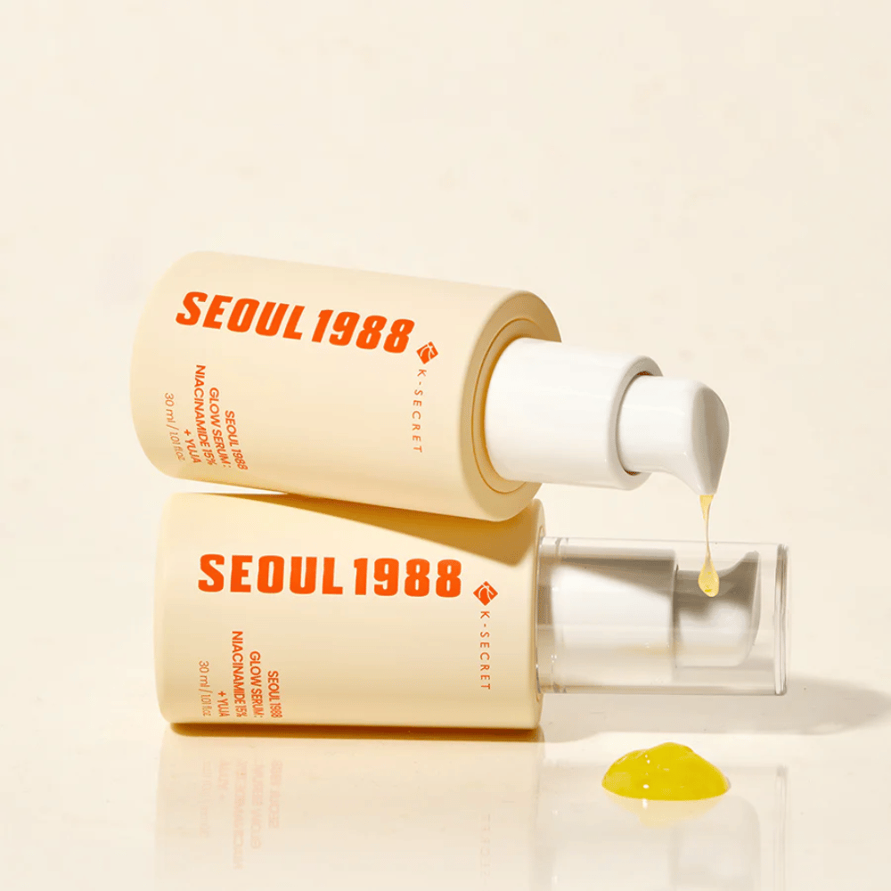 Δύο μπουκάλια Seoul 1988 Glow Serum ξαπλωμένα και όρθια, με κίτρινο ορό να στάζει από την αντλία.