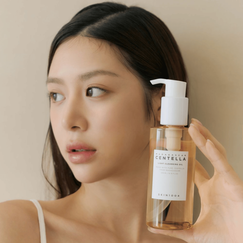 Μια γυναίκα που κρατάει ένα μπουκάλι SKIN1004 Madagascar Centella Light Cleansing Oil 200 ml καθαριστικού προσώπου.