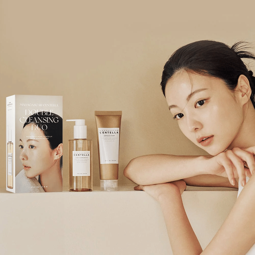 SKIN1004 Madagascar Centella Double Cleansing Duo Set με κουτί, καθαριστικό με βάση το λάδι, αφρώδες καθαριστικό και μοντέλο με ενυδατωμένο δέρμα σε μπεζ φόντο.
