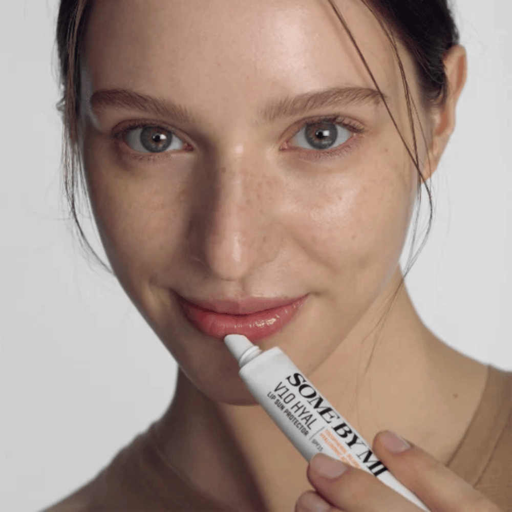 Μια γυναίκα κρατάει ένα σωληνάριο V10 Hyal Lip Sun Protector SPF15 7ml βάλσαμο χειλιών για αντηλιακή προστασία και ενυδάτωση, από SOME BY MI.