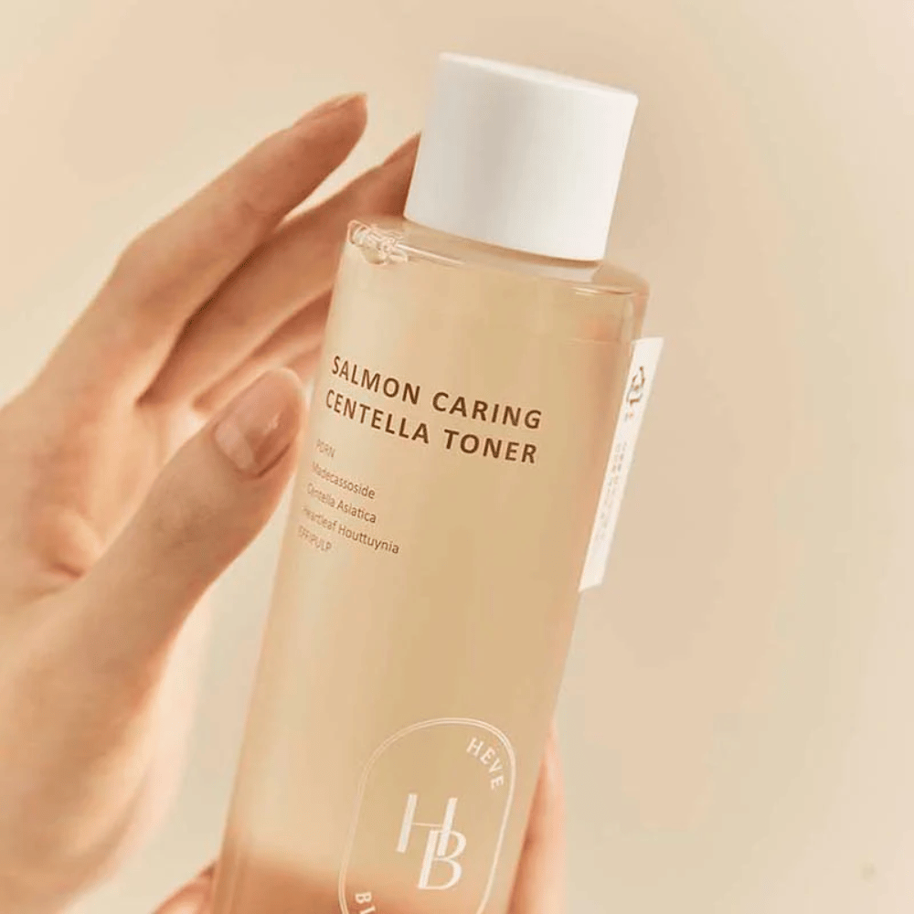 Κοντινό πλάνο του Salmon Caring Centella Toner στο χέρι – καταπραϋντική τονωτική λοσιόν με PDRN και φυτικά εκχυλίσματα που βοηθούν στην ενίσχυση του δέρματος και στη μείωση της αίσθησης του ερεθισμού.