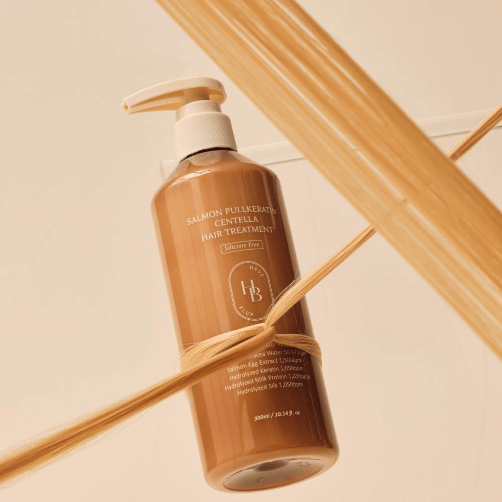 Heveblue Salmon Pullkeratin Centella Hair Treatment σε καφέ φιάλη περιτριγυρισμένη από τούφες μαλλιών. Η εικόνα αναδεικνύει τις περιποιητικές ιδιότητες της θεραπείας μαλλιών με έμφαση στη λάμψη, τη δύναμη και τα μεταξένια απαλά μαλλιά.