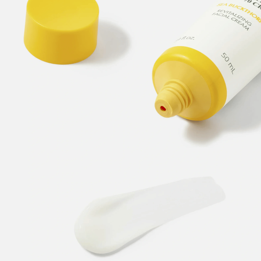 1. Purito SEOUL Sea Buckthorn Vital 70 Cream – κοντινό πλάνο της ελαφριάς λευκής υφής της κρέμας προσώπου δίπλα σε ανοιχτό σωληνάριο με κίτρινο καπάκι