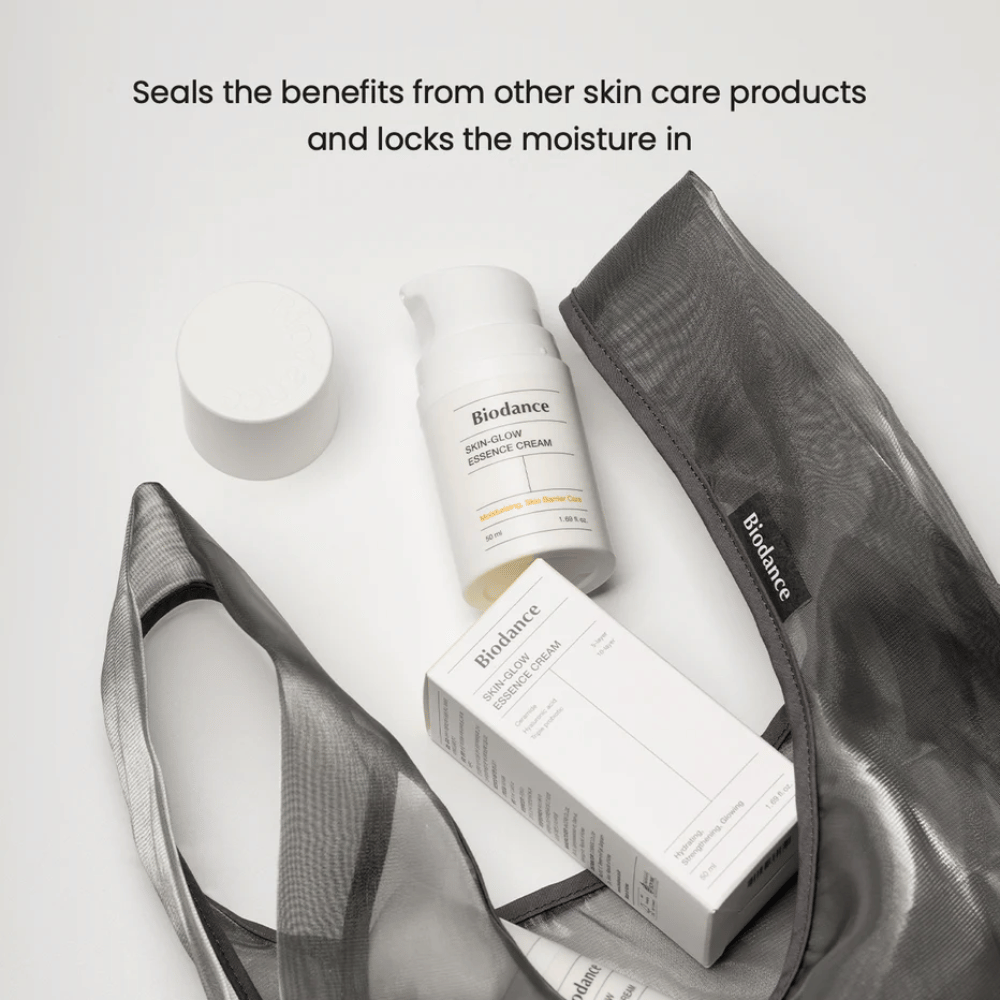 Biodance Skin-Glow Essence Cream σε εστίαση μαζί με τη συσκευασία προϊόντος και μια μαύρη διαφανή νεσεσέρ, με κείμενο από πάνω που τονίζει την ικανότητα της κρέμας να εγκλωβίζει την υγρασία και να ενισχύει την επίδραση άλλων προϊόντων περιποίησης δέρματος.
