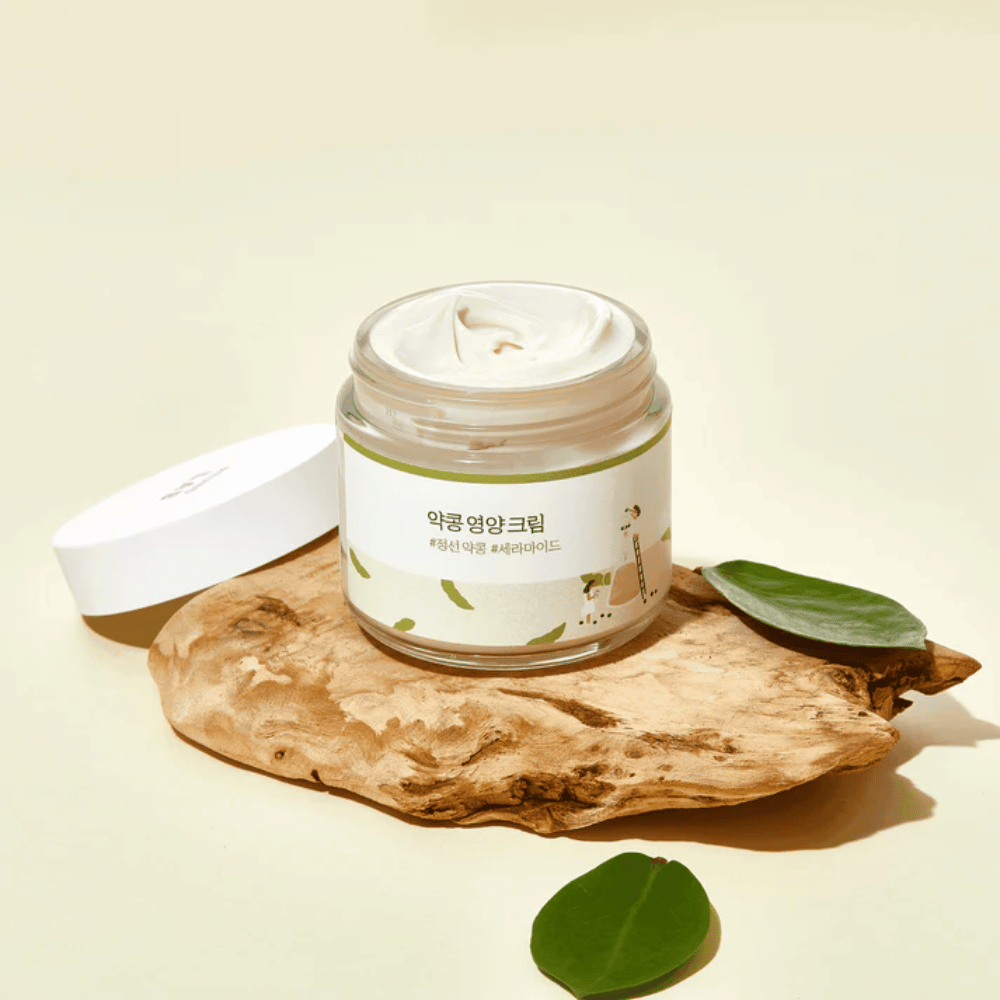 Mixsoon Soybean Nourishing Cream σε ανοιχτό βάζο πάνω σε ξύλινο κομμάτι με πράσινα φύλλα. Μια θρεπτική κρέμα με ζυμωμένα φασόλια σόγιας και κεραμίδια.