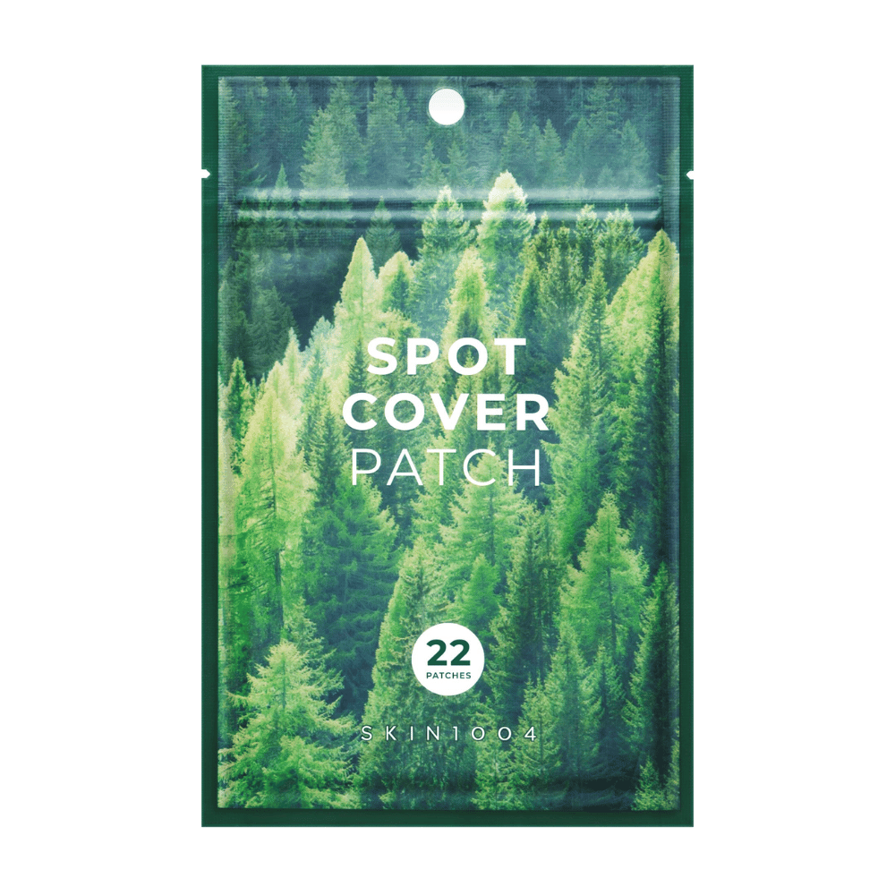 Συσκευασία με "Spot Cover Patch" που περιέχει 22 επιθέματα, σχεδιασμένη με ένα πράσινο δάσος. Το κείμενο "SPOT COVER PATCH" είναι τυπωμένο με λευκό στο μπροστινό μέρος, και ένας κύκλος σημειώνει τον αριθμό των επιθεμάτων. Το προϊόν είναι από τη μάρκα SKIN1004.