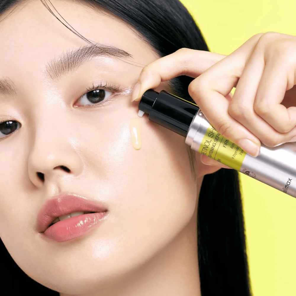 Μοντέλο εφαρμόζει το The Vita-A Retinol Shot Tightening Serum από Tiam κοντά στην περιοχή των ματιών, με έμφαση στη λάμψη του δέρματος και την κίτρινη σύσταση του ορού.