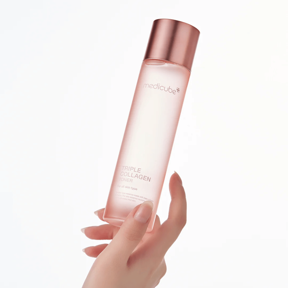 Χέρι που κρατάει ένα ροζ μπουκάλι του Medicube Triple Collagen Toner 4.0, μια ενυδατική και συσφικτική τονωτική λοσιόν για όλους τους τύπους δέρματος.