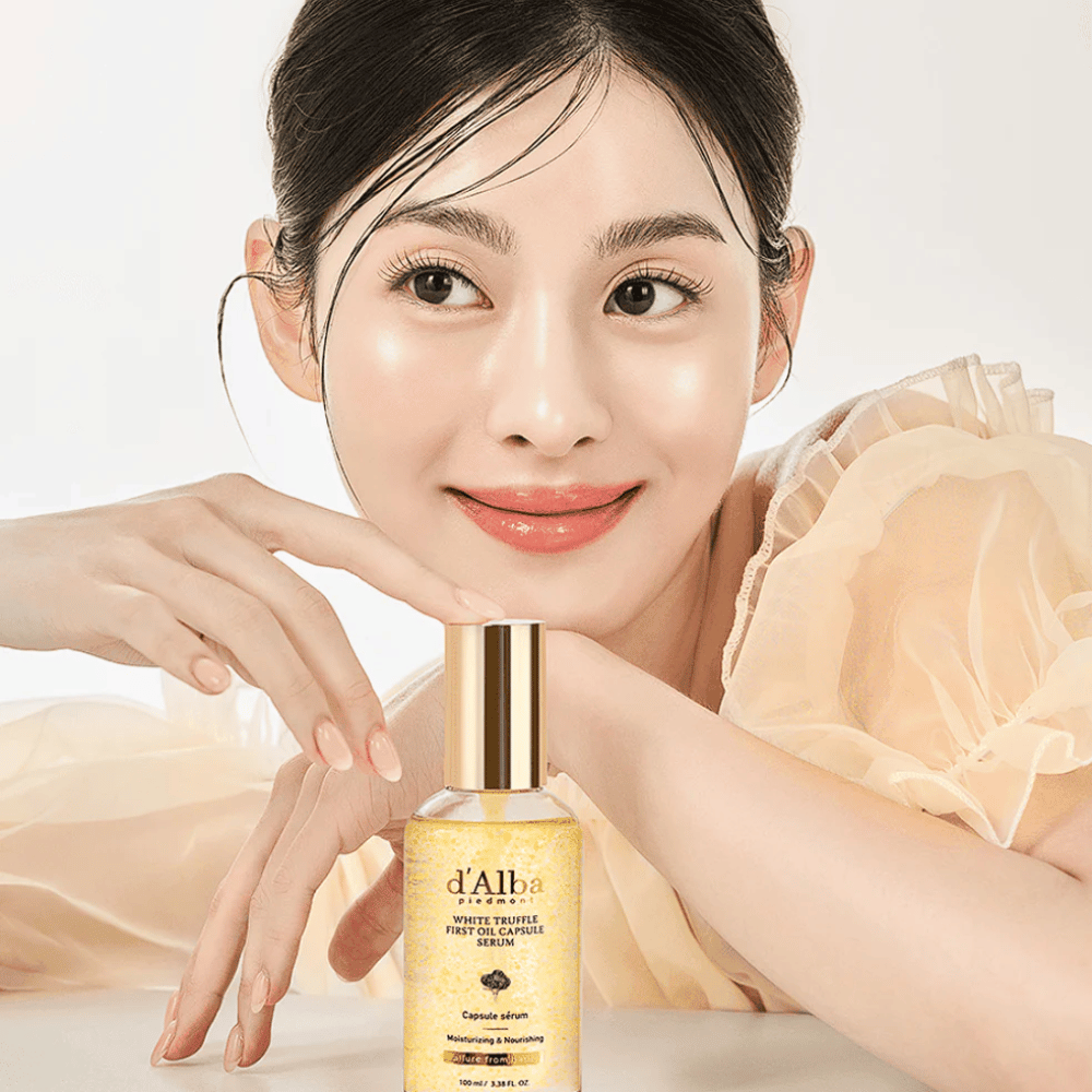 Modell i ljus klänning ler mjukt bredvid d'Alba White Truffle First Oil Capsule Serum.