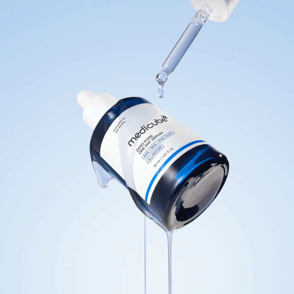 Μπουκάλι από Medicube Zero Pore One Day Serum με πιπέτα και σταγόνες ορού που τρέχουν σε ανοιχτό μπλε φόντο.