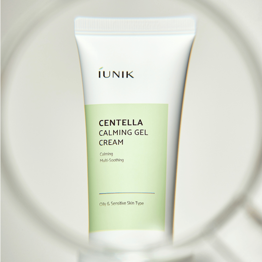 Ένας σωλήνας iUNIK Centella Calming Gel Cream με λευκό και ανοιχτό πράσινο σχέδιο στέκεται όρθιος, ορατός μέσα από ένα στρογγυλό πλαίσιο που μοιάζει με μεγεθυντικό φακό.