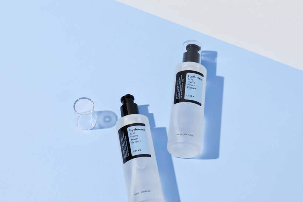 Το COSRX:s Hyaluronic Acid Hydra Power Essence 100ml παρέχει ενυδατικά οφέλη σε μπλε επιφάνεια.