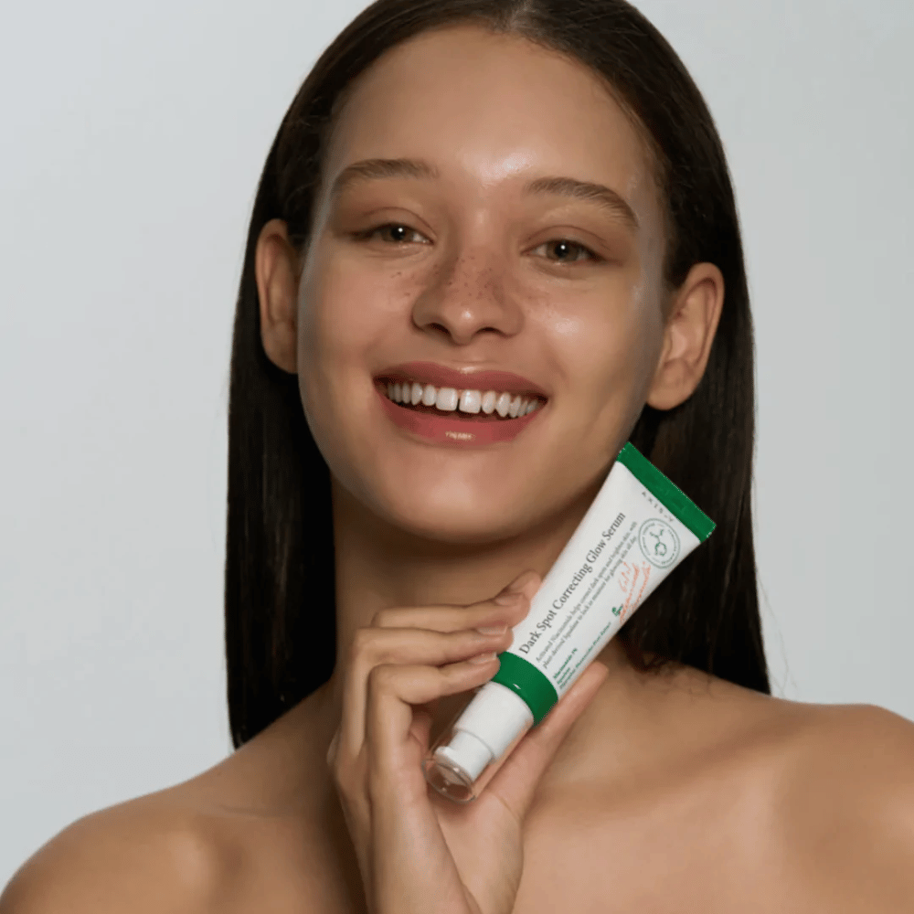 Μια νεαρή γυναίκα κρατά έναν σωλήνα με AXIS - Y Dark Spot Correcting Glow Serum 50ml.
