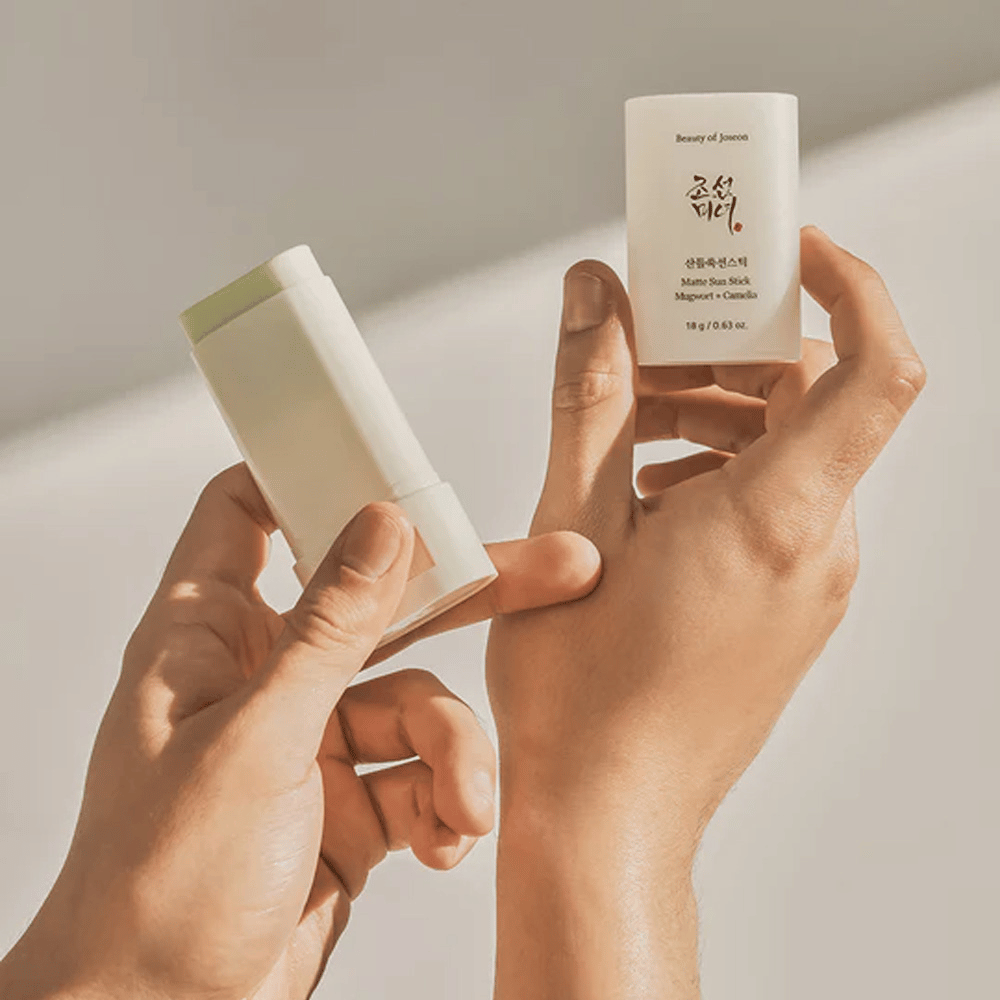 Δύο χέρια που κρατούν ένα στικ του Beauty of Joseon's Ματ Sun Stick 18g SPF50 PA++++.