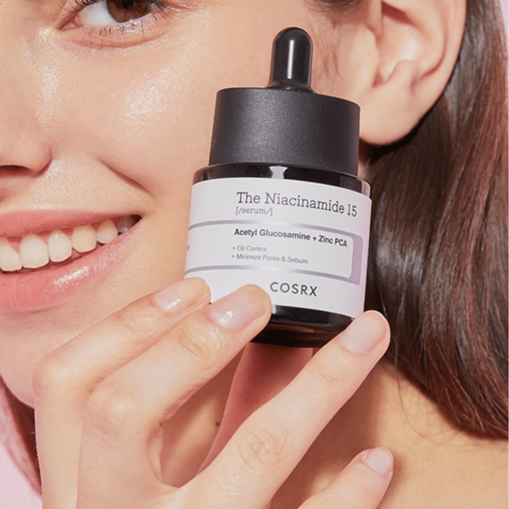 Μια γυναίκα κρατάει ένα μπουκάλι από COSRX Niacinamide 15 Serum 20ml για νιασιναμίδη και την παραγωγή σμήγματος.