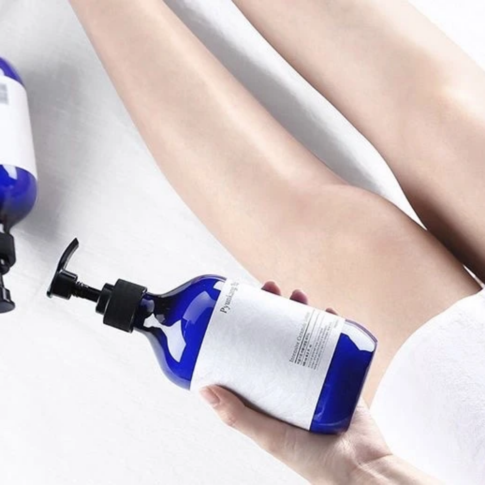 Μια γυναίκα που κρατάει ένα μπουκάλι Pyunkang Yul Intensive Ceramide Lotion 500ml δίπλα στα πόδια της.