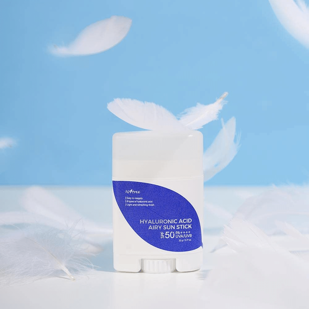Ένα Isntree Hyaluronic Acid Airy Sun Stick με SPF 50+ και Υαλουρονικό Οξύ, διακοσμημένο με λευκά φτερά.