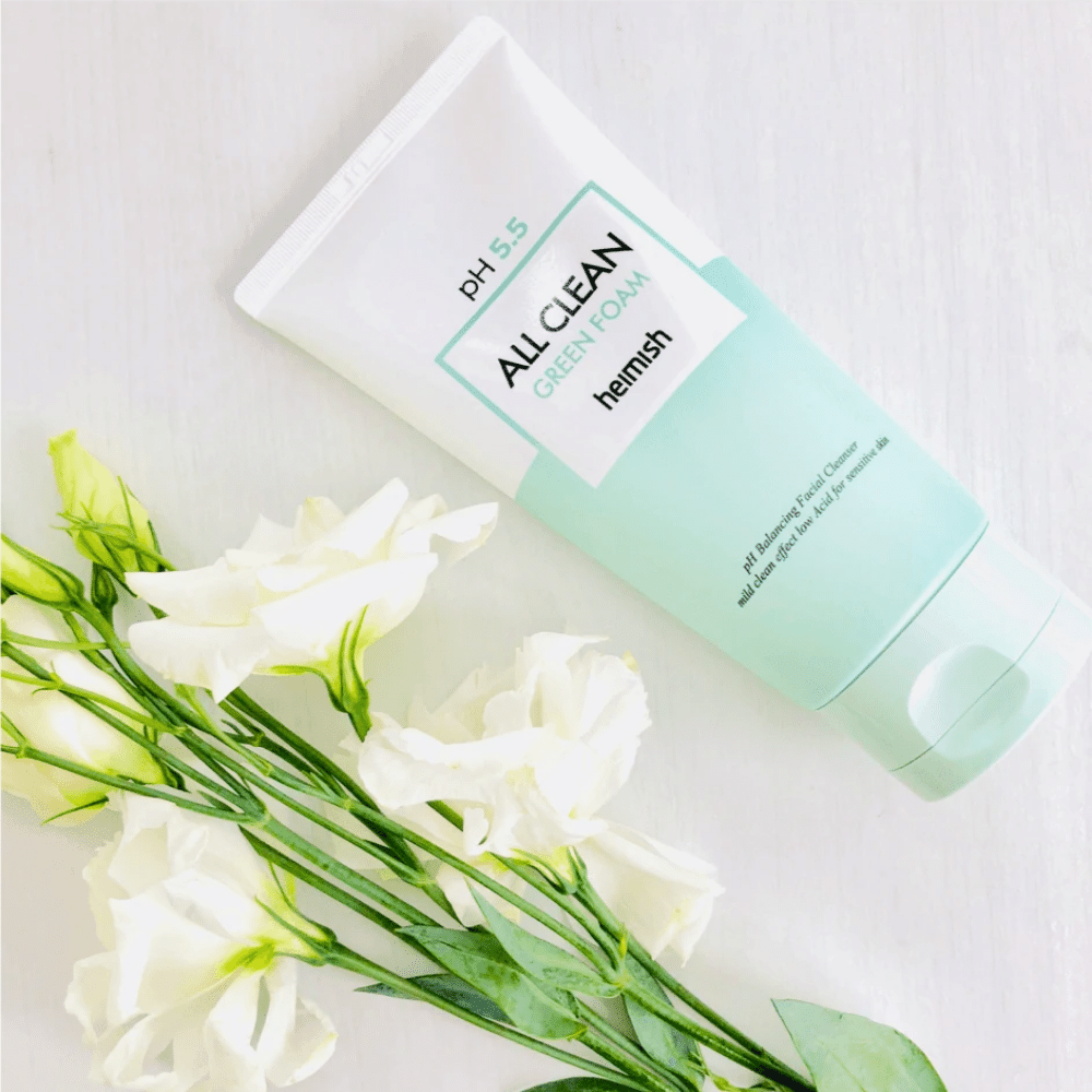 Ένας σωλήνας heimish All Clean Green Foam 150ml δίπλα σε λευκά λουλούδια.